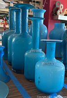 Group of five blue glass vases of varying heights displayed on table