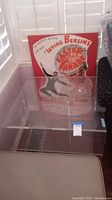 Front view of clear Lucite end table with musical poster in the background