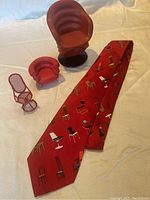 Photo showing three miniature Vitra chairs with detailed design and red color tones, plus the chair-themed red necktie.