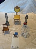 Five miniature chairs arranged on fabric background with lot tag visible