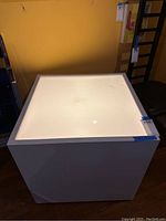 Front angled view of white cube light table showing top lit panel and smooth sides.