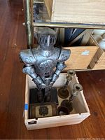 Metal knight statue with three brass candle holders and small chest in wooden box.