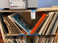 Top shelf showing two sections of vinyl records in paper/cardboard sleeves.