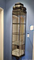 Full view of tall glass and metal wall-mounted display case with three shelves showing overall structure and design.