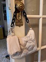 Side view showing the small matching quilted pouch attached to the handbag and the black chain-link strap with gold hardware.