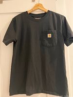 Black Carhartt women's T-shirt with chest pocket showing Carhartt logo patch.