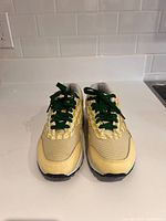 Front view of the limited edition Nike Air Max Lemonades sneaker, showing yellow and cream mesh and leather upper with green laces threaded.