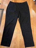 Front view of black Uniqlo dress pants showing slim fit, fabric texture, closure, and front pockets.