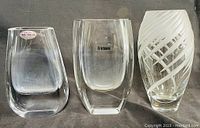 Three vintage crystal vases arranged side by side on a dark cloth background.