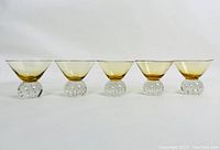 Front view of all 5 amber-topped, clear controlled bubble base wine goblets in a row.