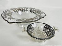 Photo showing both antique silver overlay glass pieces together on white background.