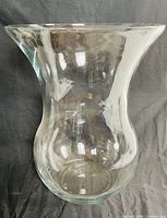 Front angle view of a large, thick clear glass vase with a flared rim and rounded body showing the shape and thickness of the vase.