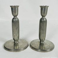 Pair of MCM pewter candlesticks, showing front and base markings.