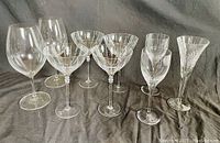 Nine crystal stemware glasses arranged in two rows showing clear and cut crystal designs including Waterford glass on the right.