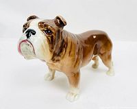 Angled front view showing facial details and posture of the bulldog figurine with brown and white glaze.