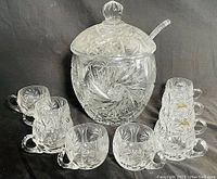 Full set view showing punch bowl, matching lid, clear ladle, and 10 matching small punch cups in a semicircle.