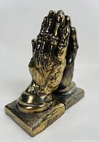 Pair of cast metal praying hands bookends shown side by side.