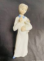 Porcelain figurine of a young girl holding a cat, shown from an angle to reveal details of face and cat.