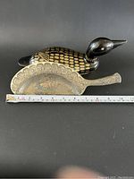 Photo showing both antique items side by side with a measuring tape showing approximately 12 inches length for the brass retriever.