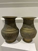 Front view of two brass vases showing embossed Buddhism themed patterns