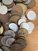 Close view of assorted antique coins showing various metals and designs including a coin with a hole in the center.