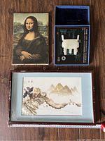 Three decorative items including Mona Lisa canvas, framed painting, and boxed white sculpture.