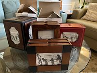 Overview showing five photo albums with wooden covers in assorted colors and silhouette design windows.
