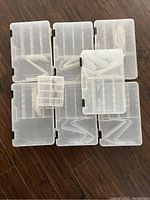 Seven clear plastic boxes arranged on floor, showing size comparison and latch clips.