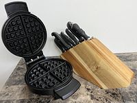 Overview of waffle maker open showing non-stick waffle grids and walnut knife block with six knives.