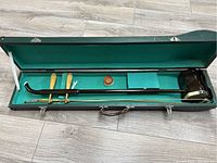 Open green case showing the Erhu instrument, two bow sticks, and a small container inside.