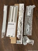 Top view of laundry room items, including drying rack parts, cords, hooks, and rods all laid out on a wooden floor.
