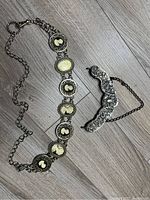 Full view of the cameo belt and decorative bag handle laid out on the floor.