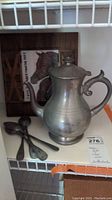 Photo showing pewter pitcher, utensils, and wooden picture frame with horse artwork
