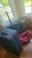 Photo showing four pieces of luggage including a red duffel bag and three suitcases on wheels by different brands.