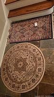 Photo of two rugs on floor: rectangular Verona rug 2'2"x3'7" with intricate pattern and fringes, and round Triumph 40" rug with central floral medallion