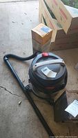 Photo showing Porter Cable shop vacuum with hose on a concrete floor near boxes