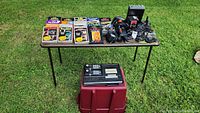 Overview of lot contents: table on grass with game cartridges, controllers, expansion module, power adapter and cables