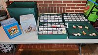 Full lot overview showing multiple boxes and bins of Christmas ornaments including nativity scenes in packaging and various resin character ornaments on display.