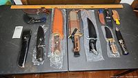 Overhead view of nine commemorative and decorative knives with sheaths