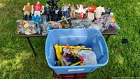 Overview of large figures on table and blue tub of accessories