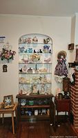 Full display of five glass-filled shelves, small tables and lamps next to a brick fireplace.