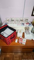 Wide view showing multiple boxed Hallmark angel ornaments with a large red and black plaid storage bag on table.