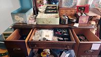 Full view of open dresser drawers and tabletop with various jewelry boxes containing assorted jewelry pieces