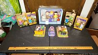 Wide view of Peanuts figurines arranged on table showing multiple boxed items including Snoopy, Woodstock, Charlie Brown, Lucy, Linus, and Sally Brown figures