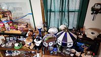 Wide shot showing multiple Penn State collectibles including stuffed lions, mugs, plates, glassware, lamps, and decorative items on a shelf.