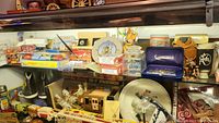 Display cabinet shelf of various Roy Rogers collectibles including toy stagecoach, plates, figurines, and packaged items