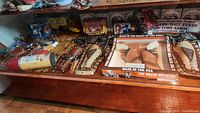 Shelf view showing two unboxed studded leather holster sets and one boxed Top Grain Cowhide holster set with toy revolvers.