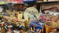 Shelf view showing assorted items: Roy Rogers tin flashlight box, ceramic mug, collector plate, toy belt and bandana, ornament