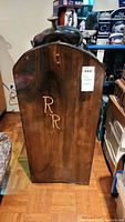 Wooden saddle stand with carved RR initials on the back panel.
