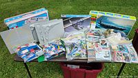 Overall lot displayed on surface showing drafting table components, bags of LEGO, toy vehicles, and trading cards
